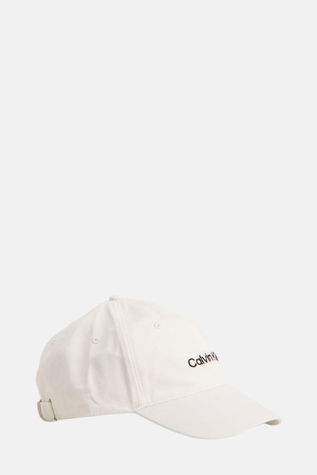 Casquette blanche de Calvin Klein, avec logo noir brodé sur le devant et boucle de réglage métallique visible.
