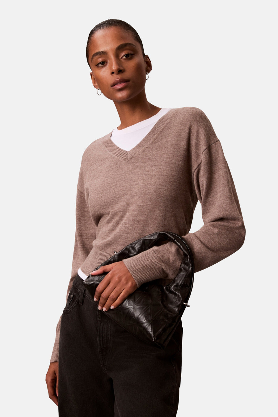 Zwarte Calvin Klein schoudertas met gewatteerd patroon, gedragen met een zwarte jeans.