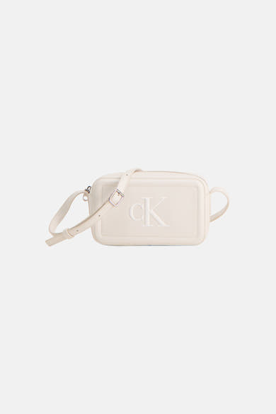Witte Calvin Klein schoudertas, gedragen met een zwarte broek en bijpassende pumps, in zijaanzicht.