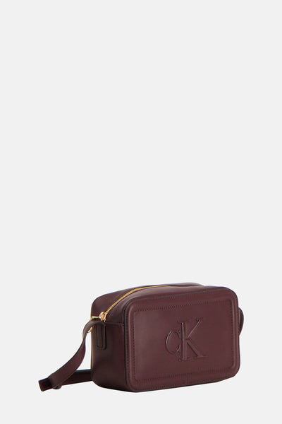 Sac à bandoulière bordeaux de Calvin Klein avec une fermeture éclair dorée et le logo en relief.