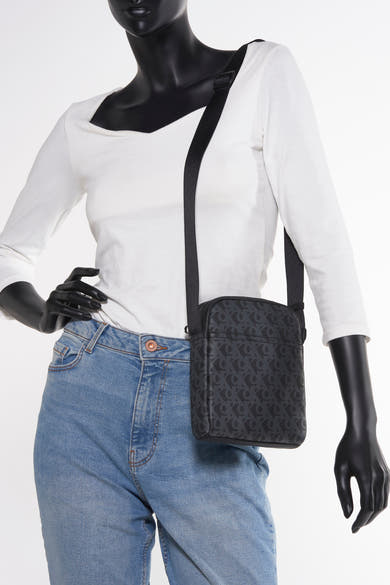 Grijze Calvin Klein schoudertas met logopatroon, gedragen met een blauwe jeans en een wit T-shirt met lange mouwen.