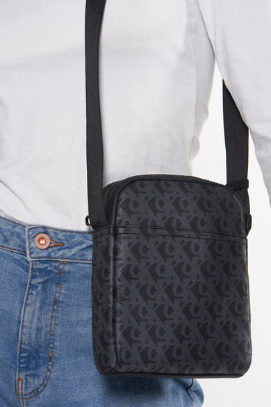 Grijze Calvin Klein schoudertas met logoprint, gedragen met een spijkerbroek en een wit T-shirt.