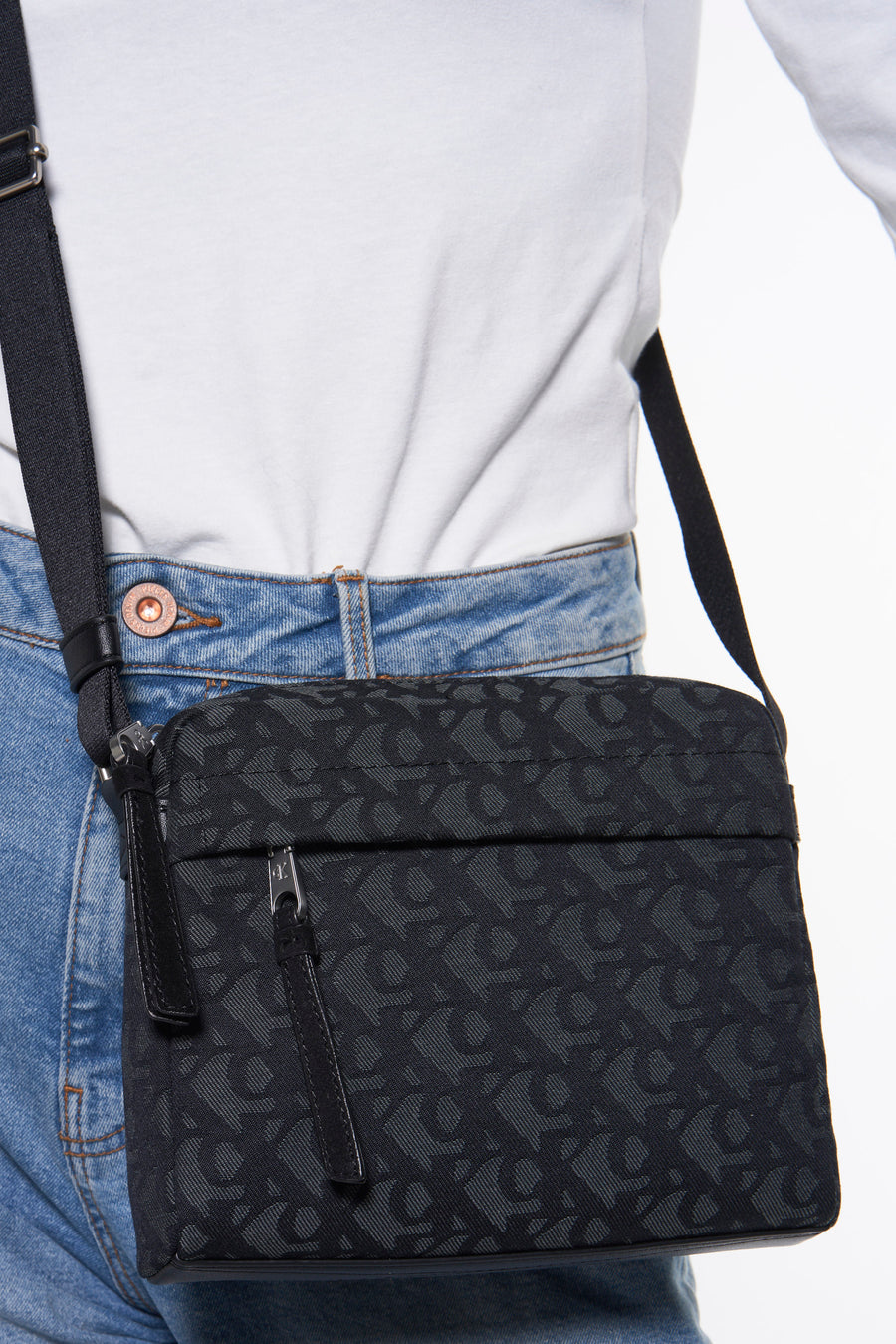 Sac à bandoulière noir de Calvin Klein, porté sur le corps, avec un motif ton sur ton.
