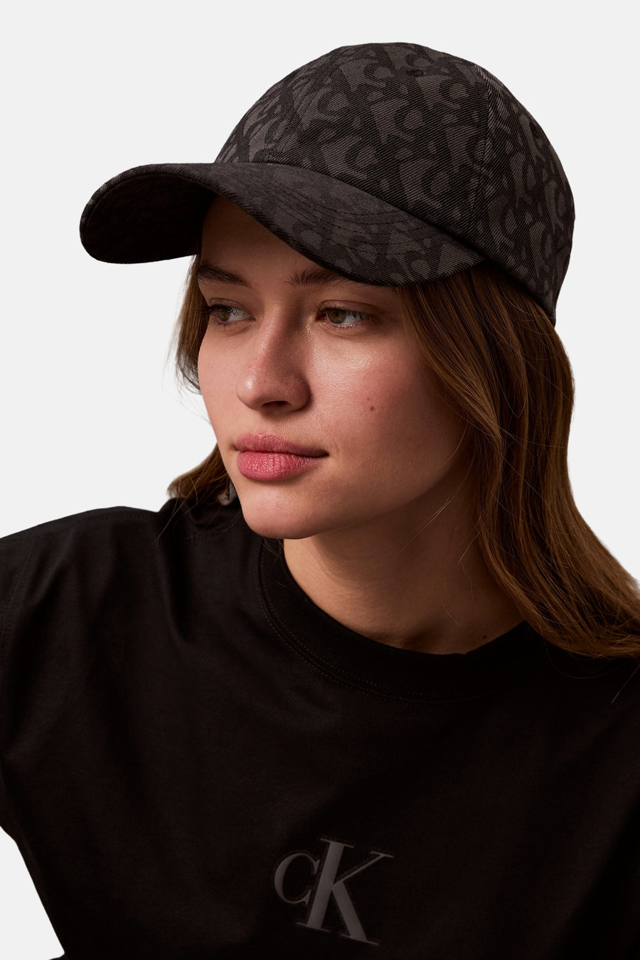 Casquette noire de Calvin Klein, avec motif ton sur ton, portée avec un t-shirt noir à logo.