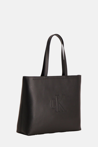 Sac à main noir de Calvin Klein, avec un logo CK ton sur ton en relief sur le devant.