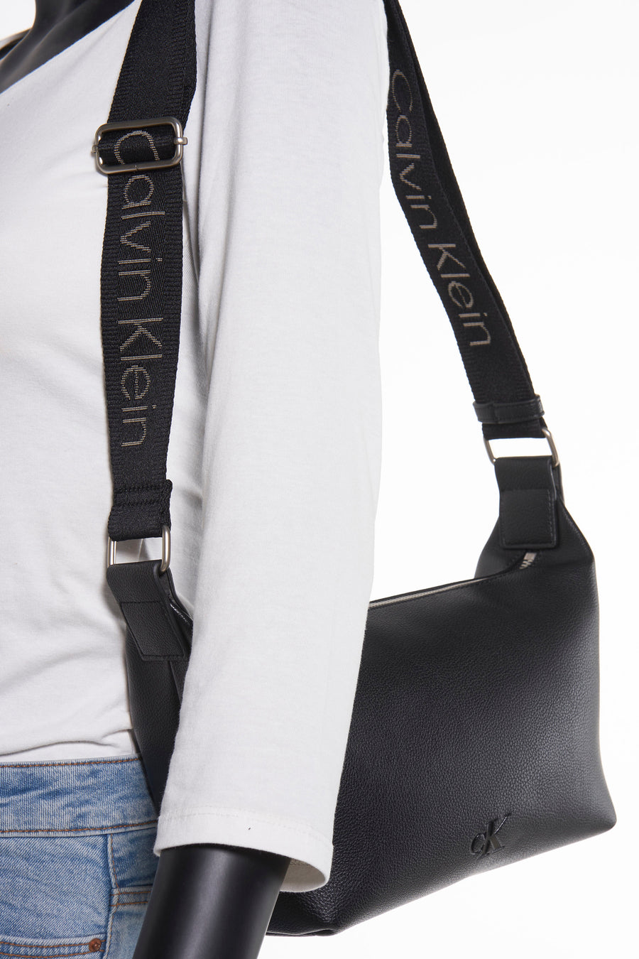 Sac à bandoulière noir en cuir synthétique de Calvin Klein, avec une bandoulière en tissu à logo.