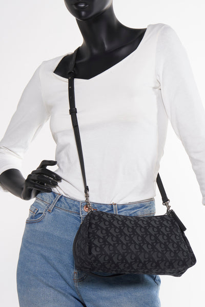 Zwarte Calvin Klein schoudertas met herhalend logo-patroon, gedragen met een blauwe jeans en een witte top.