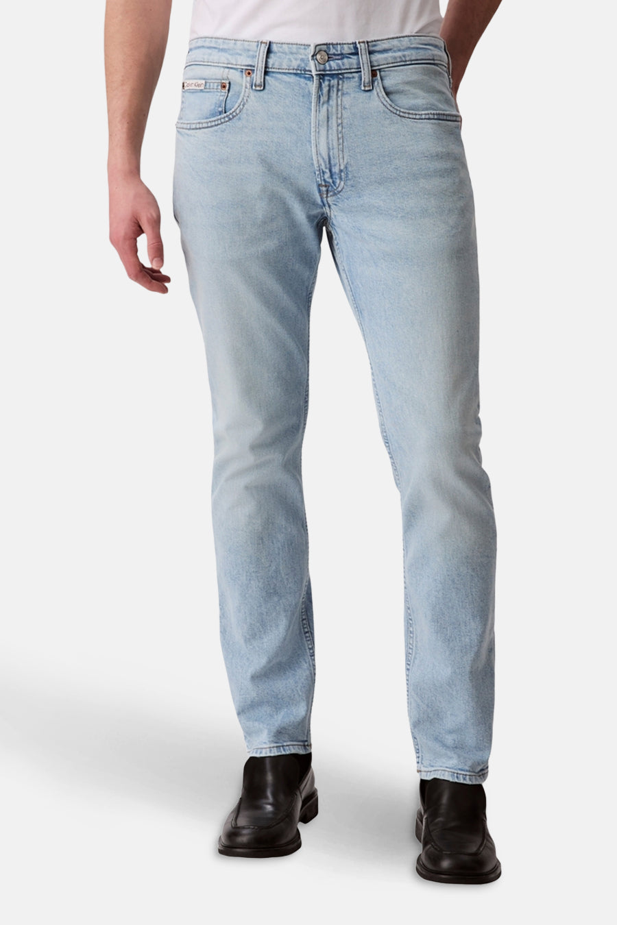 Jean slim en denim bleu clair de Calvin Klein, avec des chaussures noires.