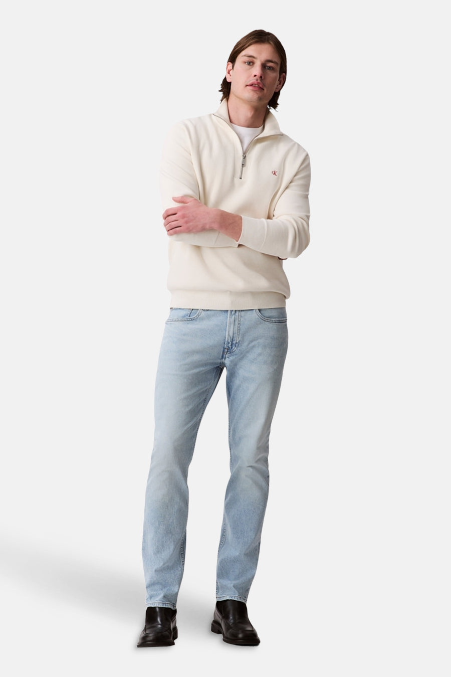 Jean slim bleu clair de Calvin Klein, porté avec un pull crème et des chaussures noires.