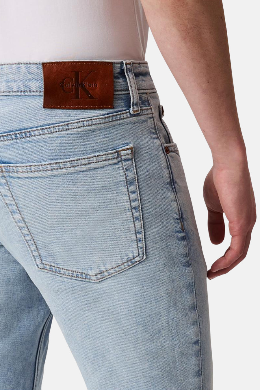 Jean slim en denim bleu clair de Calvin Klein, avec une poche arrière et étiquette logotypée en cuir marron.