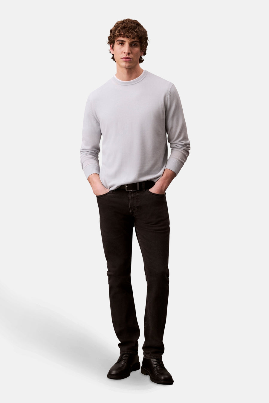 Zwarte Calvin Klein spijkerbroek, gedragen met een lichtgrijze trui en zwarte schoenen.