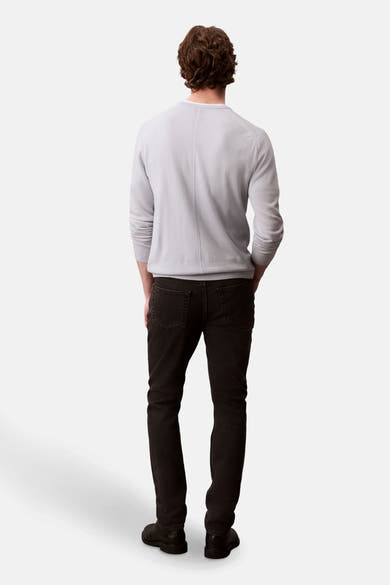 Zwarte slim fit jeans van Calvin Klein, gedragen met een lichtgrijze trui, achterzicht.