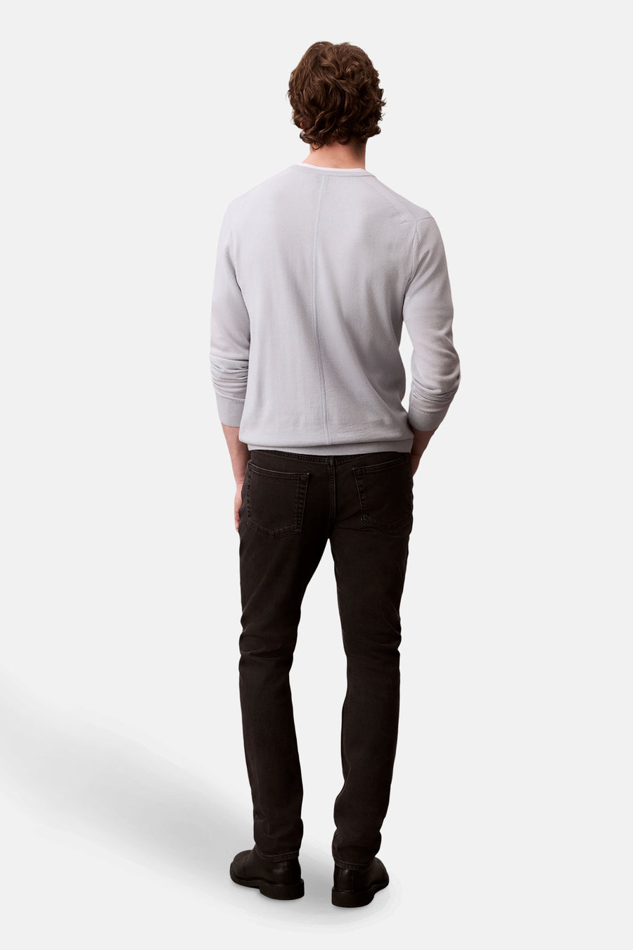 Zwarte slim fit jeans van Calvin Klein, gedragen met een lichtgrijze trui, achterzicht.