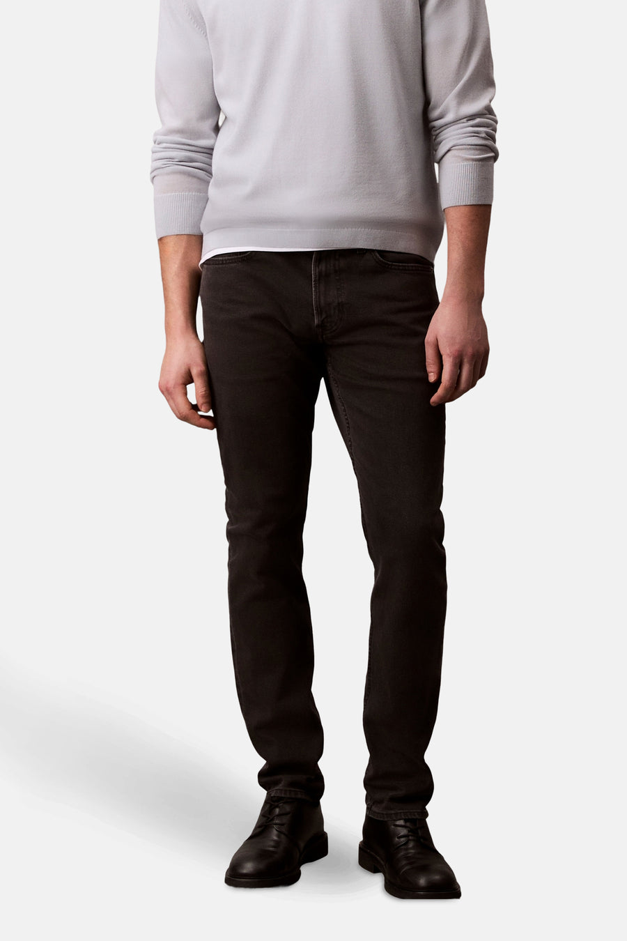 Zwarte Calvin Klein spijkerbroek, gedragen met een lichtgrijze trui en zwarte schoenen.