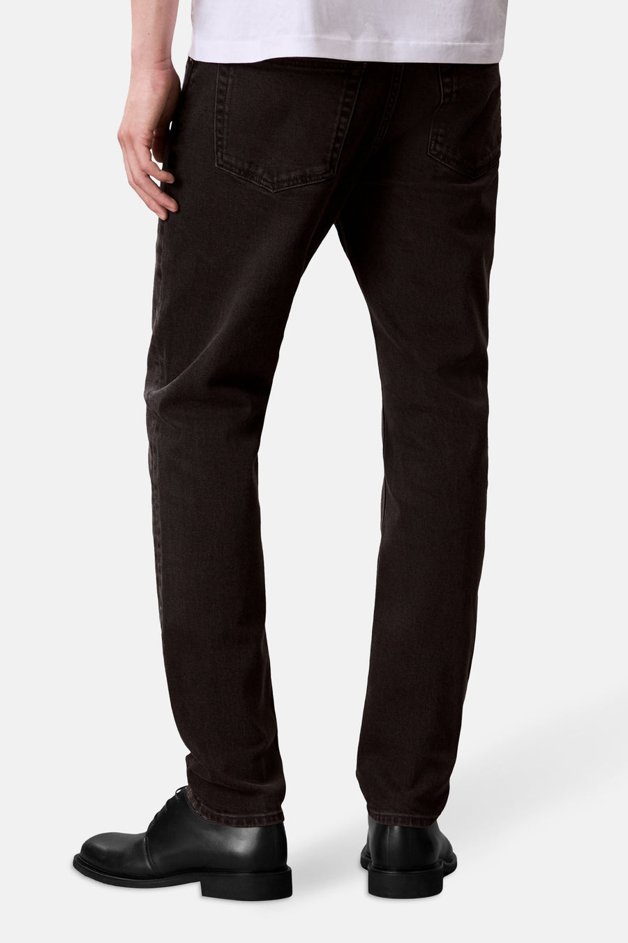 Jean fuselé en denim gris foncé de Calvin Klein, porté avec un t-shirt blanc et des chaussures noires.