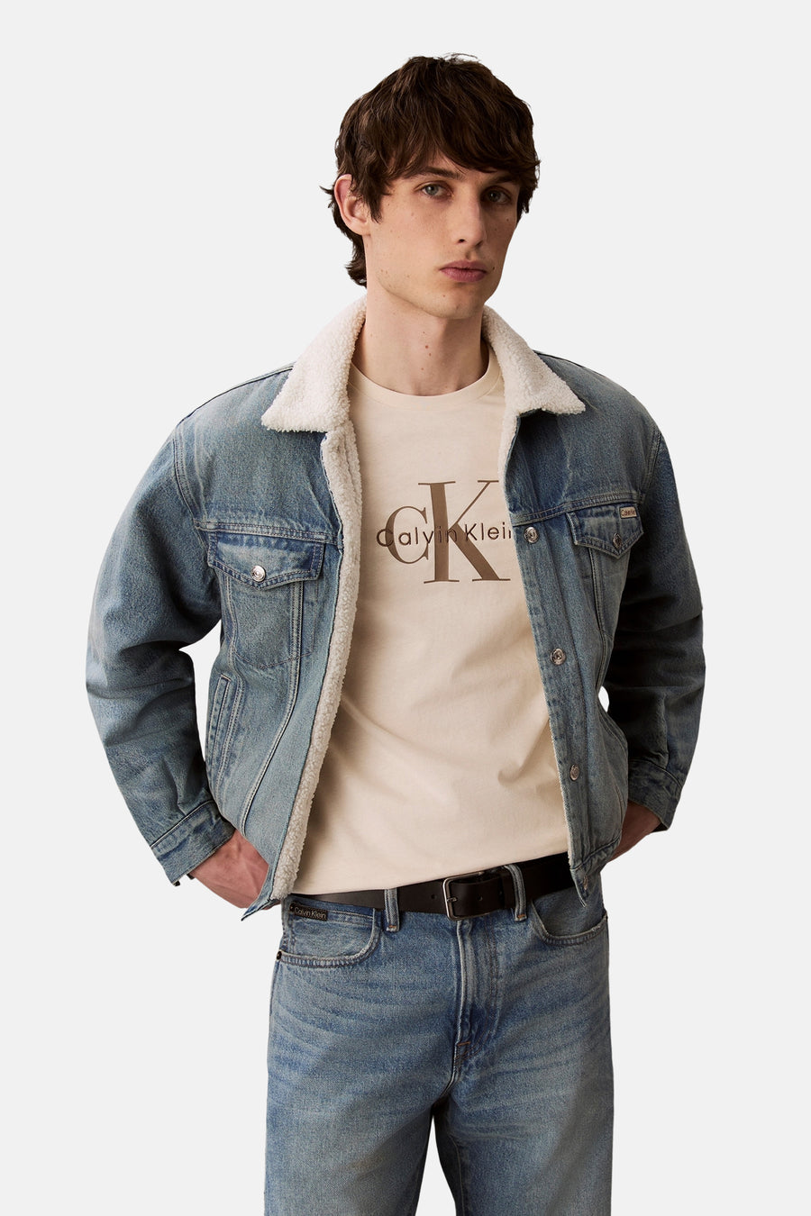 Ecru T-shirt met korte mouwen van Calvin Klein, gedragen onder een spijkerjas met schapenvachtvoering, met een blauwe spijkerbroek.