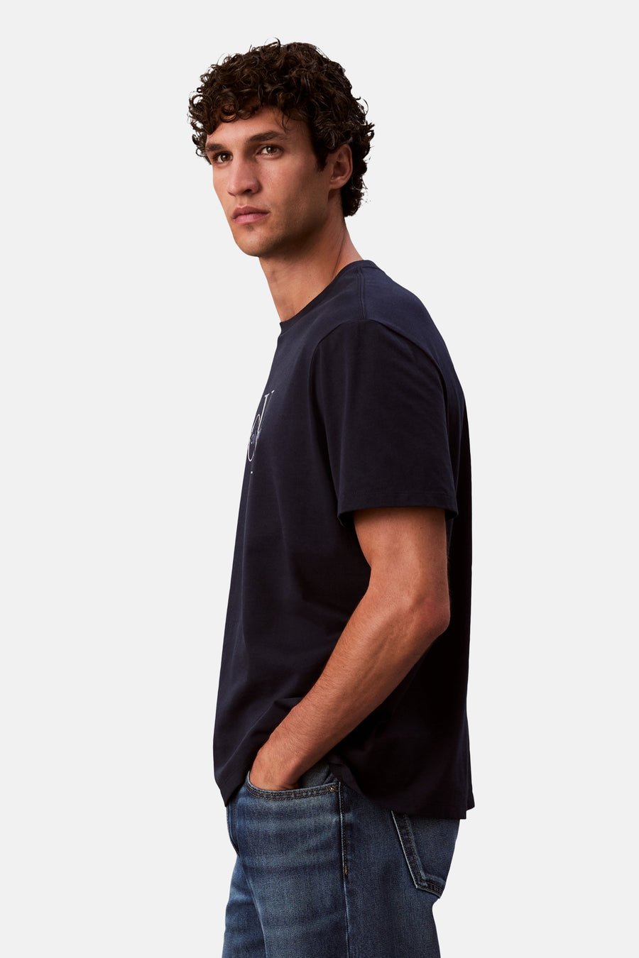 Donkerblauw T-shirt met korte mouwen van Calvin Klein, gedragen met een spijkerbroek, van opzij gezien.