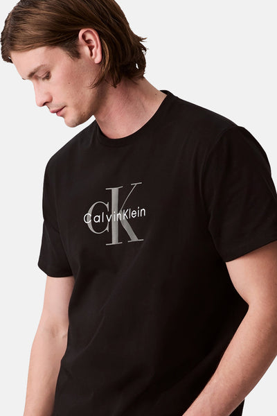 T-shirt noir à manches courtes de Calvin Klein, orné d'un logo sur le devant, porté par un homme.