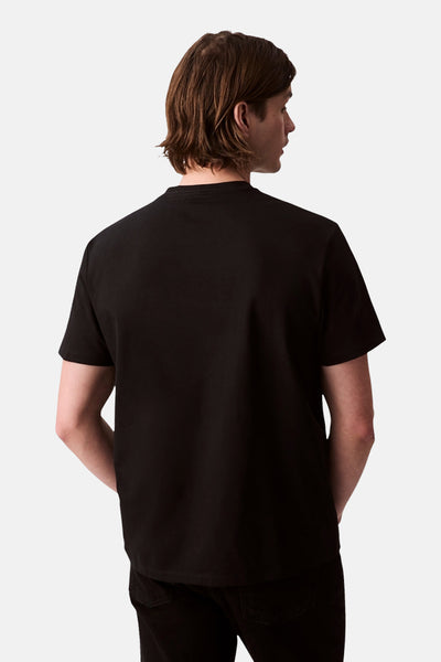 T-shirt à manches courtes noir de Calvin Klein, vu de dos, porté avec un pantalon noir.