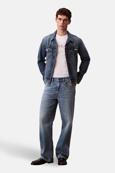T-shirt à manches courtes blanc de Calvin Klein, porté avec une veste et un jean en denim bleu.