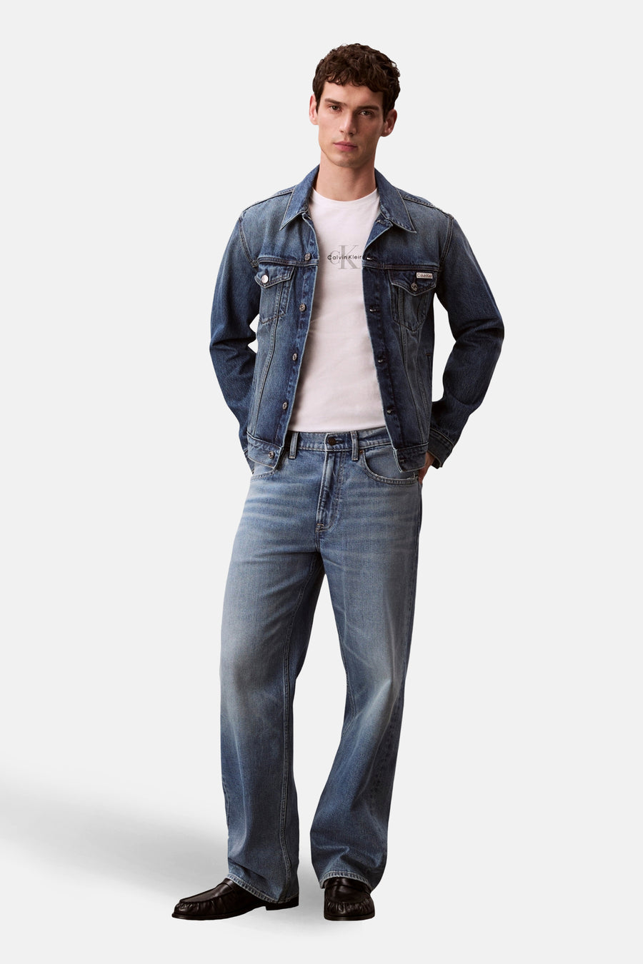 T-shirt à manches courtes blanc de Calvin Klein, porté avec une veste et un jean en denim bleu.