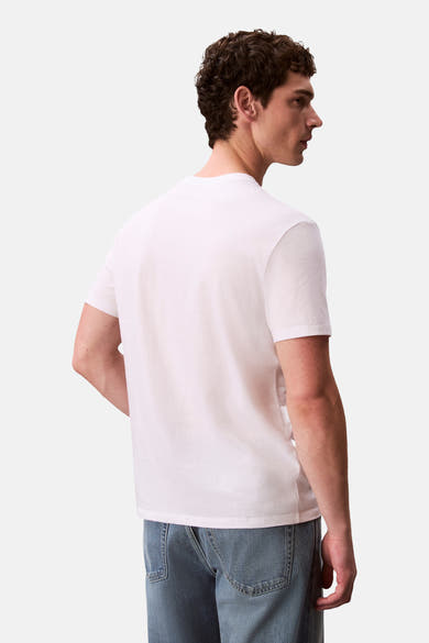 T-shirt à manches courtes blanc de Calvin Klein, avec un dos uni et porté avec un jean.