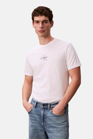 T-shirt à manches courtes blanc de Calvin Klein avec logo Calvin Klein sur la poitrine, porté par un homme en jean bleu.