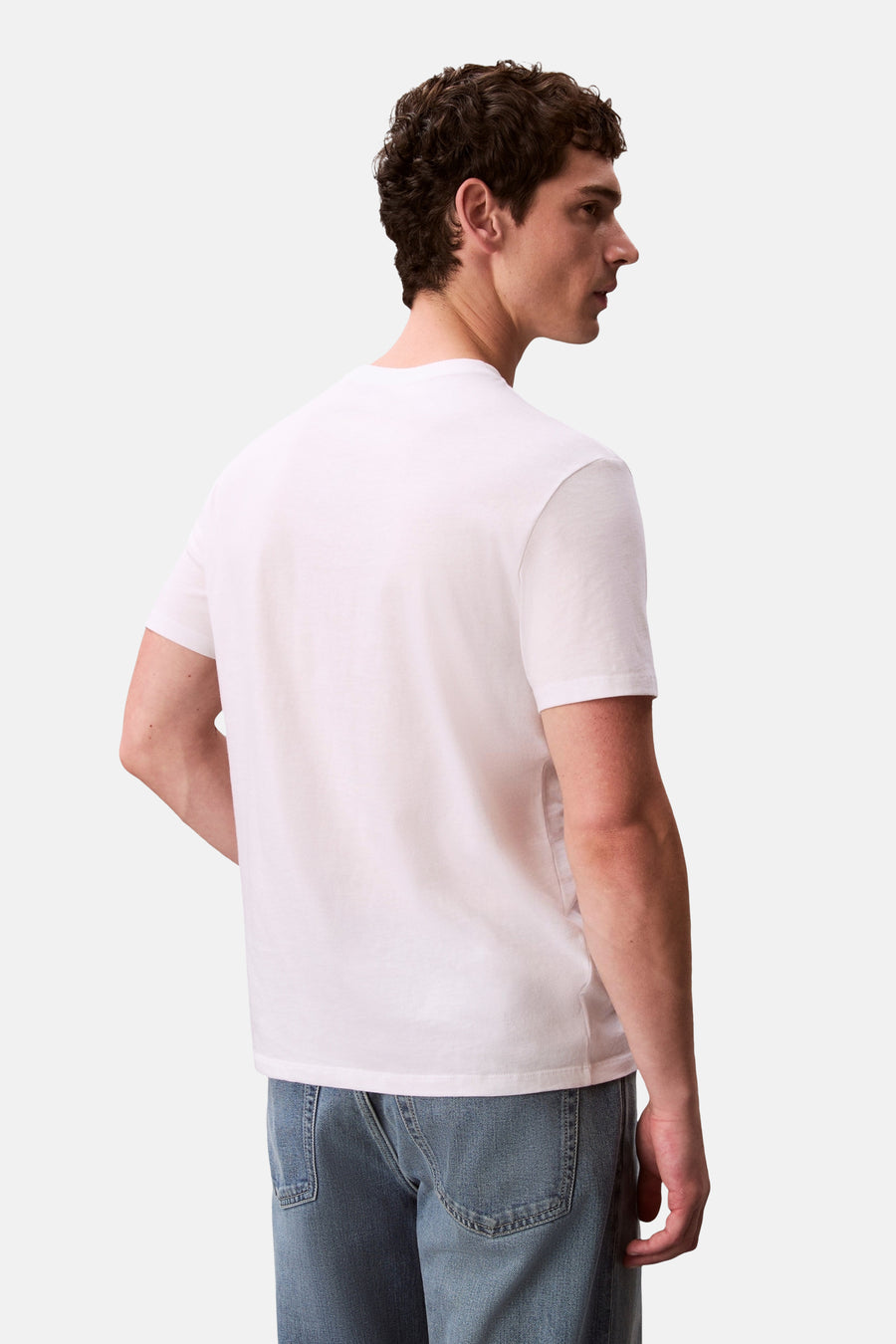 T-shirt à manches courtes blanc de Calvin Klein, porté de dos par un homme en jean.