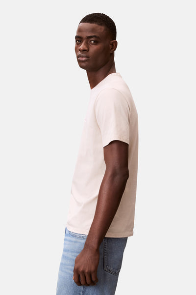 T-shirt écru à manches courtes de Calvin Klein, porté avec un jean bleu clair, vue de côté.