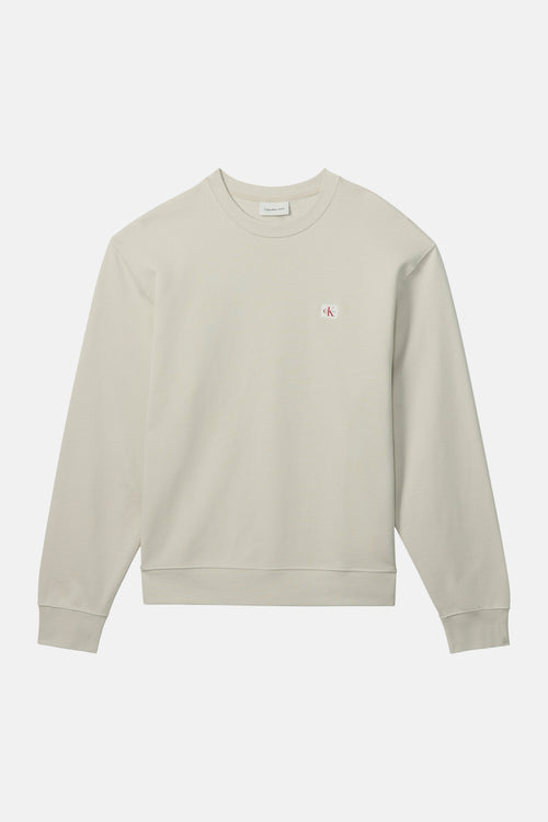Sweat-shirt beige en coton, de Calvin Klein, avec un logo discret sur la poitrine.
