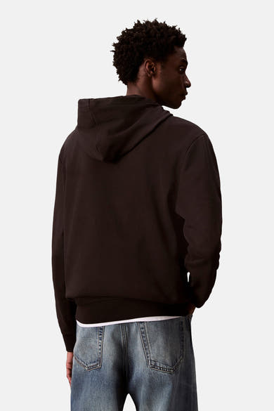 Sweat à capuche noir de Calvin Klein, porté avec un t-shirt blanc et un jean bleu, vue de dos.
