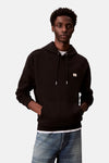 Sweat à capuche noir par Calvin Klein, avec cordon de serrage et poche kangourou, porté sur un jean bleu.