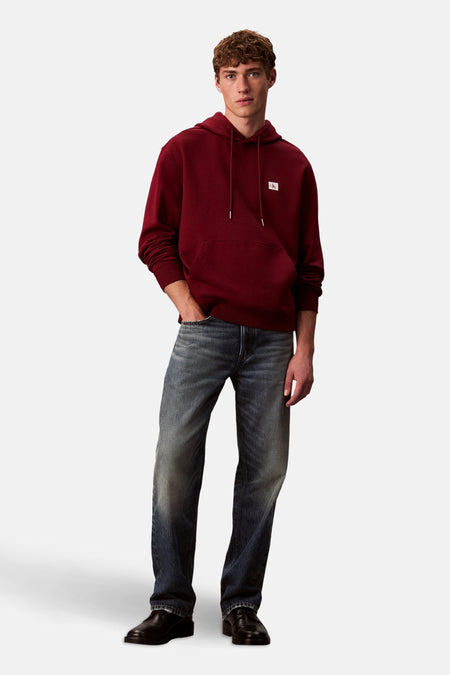 Bordeaux hoodie van Calvin Klein, gedragen met een verbleekte spijkerbroek en zwarte schoenen.