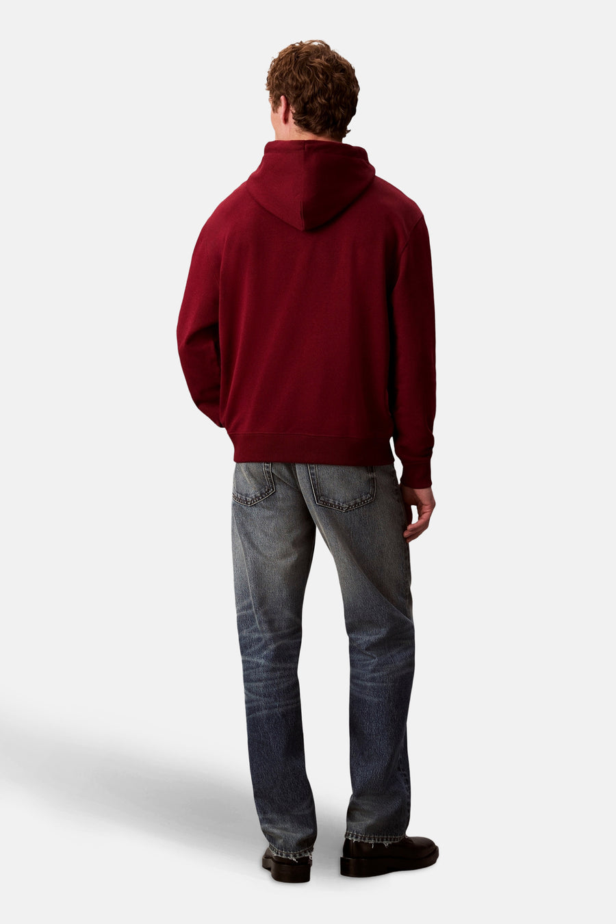 Bordeaux Calvin Klein hoodie, gedragen met een lichtgewassen spijkerbroek en zwarte schoenen, achtergezicht.
