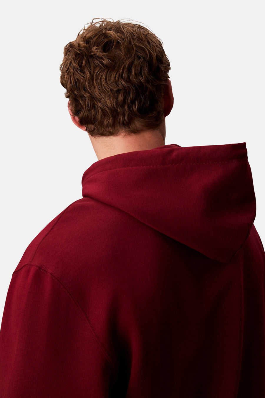 Bordeaux Calvin Klein hoodie, van achteren gezien, met een losse capuchon en golvend bruin haar zichtbaar.