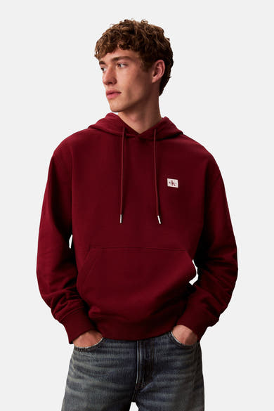 Bordeaux hoodie van Calvin Klein, met trekkoord en kangoeroezak, gedragen met een spijkerbroek.
