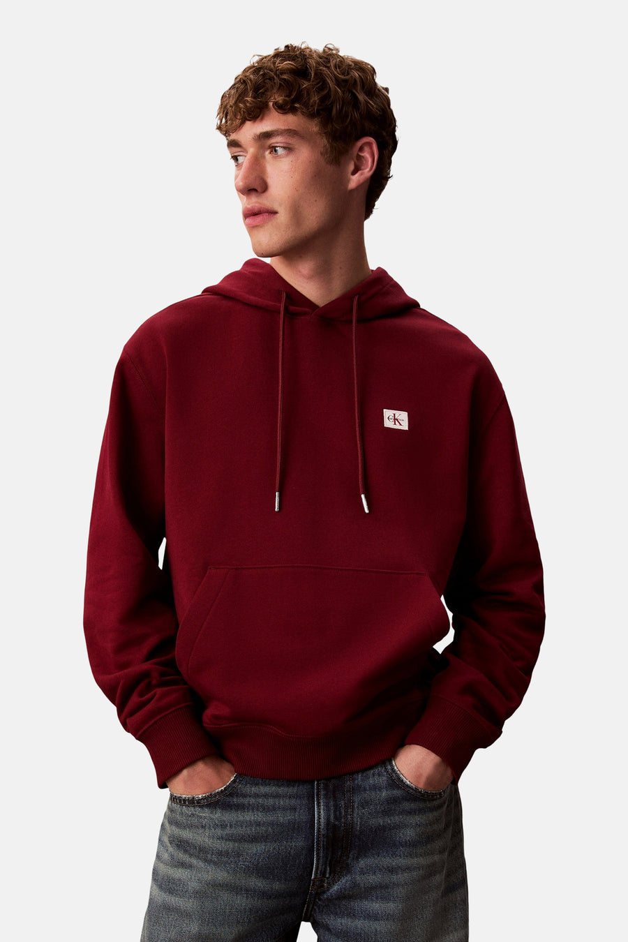 Bordeaux hoodie van Calvin Klein, met trekkoord en kangoeroezak, gedragen met een spijkerbroek.