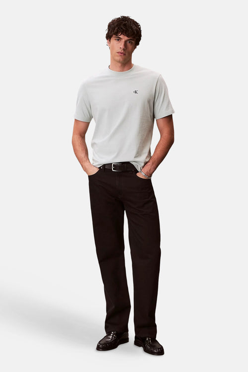 T-shirt bleu à manches courtes de Calvin Klein, avec un logo sur la poitrine et porté avec un pantalon noir et des mocassins.