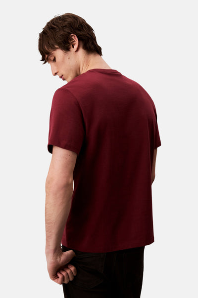 T-shirt bordeaux à manches courtes de Calvin Klein, porté avec un pantalon foncé, vue de dos.
