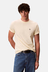 T-shirt à manches courtes jaune de Calvin Klein porté avec un jean bleu et une ceinture noire.