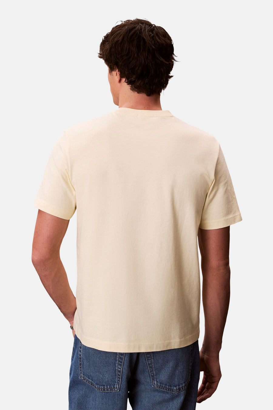 T-shirt à manches courtes jaune de Calvin Klein, porté avec un jean bleu, vue de dos.