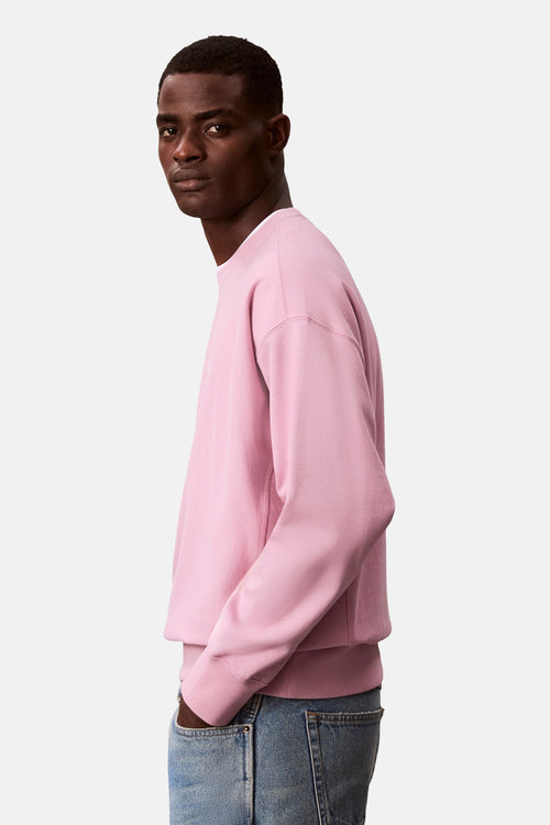 Sweat rose de Calvin Klein, porté avec un jean, vu de côté.