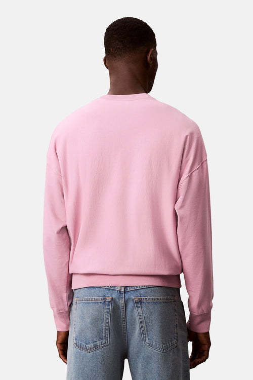 Sweat rose col rond de Calvin Klein, porté avec un jean bleu délavé, vue de dos.
