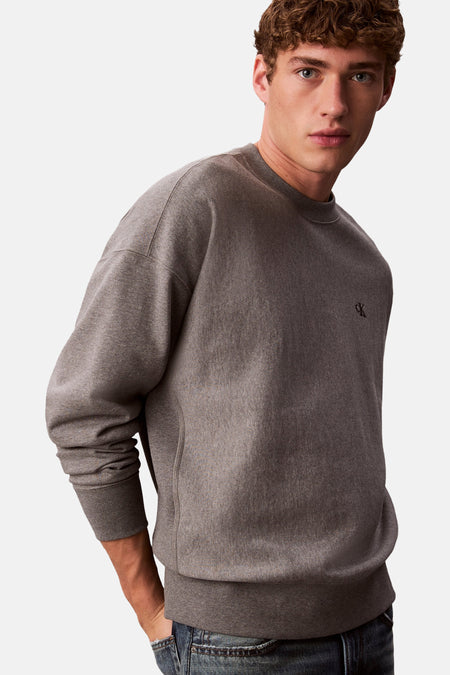 Grijze Calvin Klein sweatshirt, met geborduurd logo op de voorkant en gedragen met een spijkerbroek.