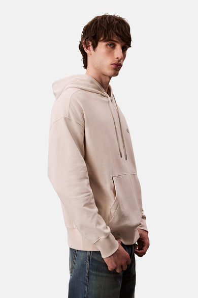 Ecru hoodie van Calvin Klein, met trekkoord en kangoeroezak, gedragen met een blauwe jeans.