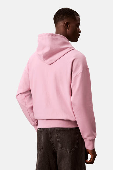 Sweat à capuche rose de Calvin Klein, porté avec un jean foncé, de dos.