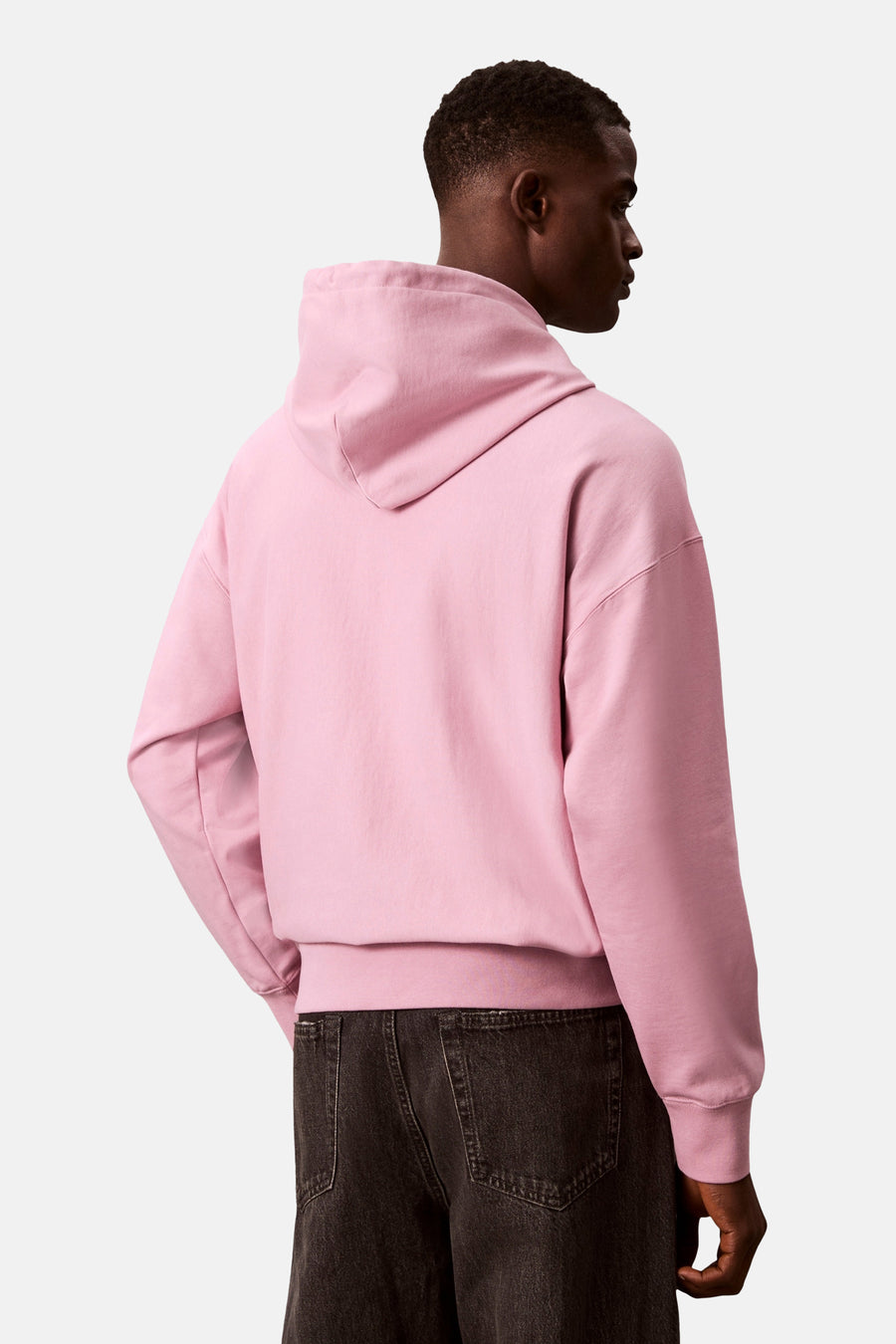 Sweat à capuche rose de Calvin Klein, porté avec un jean foncé, de dos.
