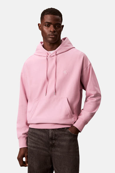 Sweat à capuche rose de Calvin Klein avec cordon de serrage et poche kangourou, porté avec un jean.