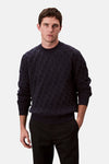 Sweat bleu marine de Calvin Klein, avec un motif texturé discret, porté avec un pantalon noir.
