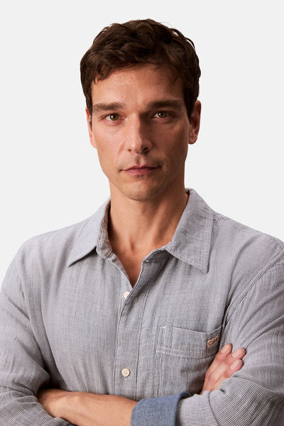 Chemise à manches longues bleue rayée, par Calvin Klein, avec des manches boutonnées et une poche poitrine.